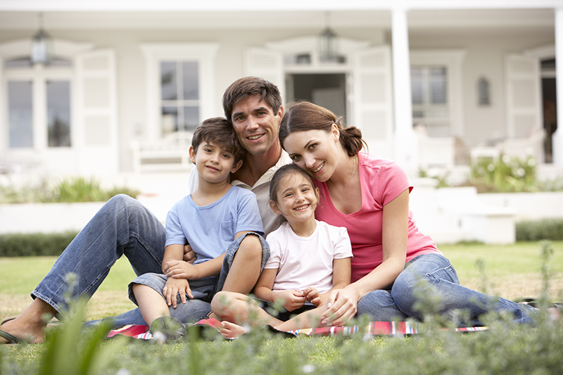 Family Sitting Outside House On Lawn